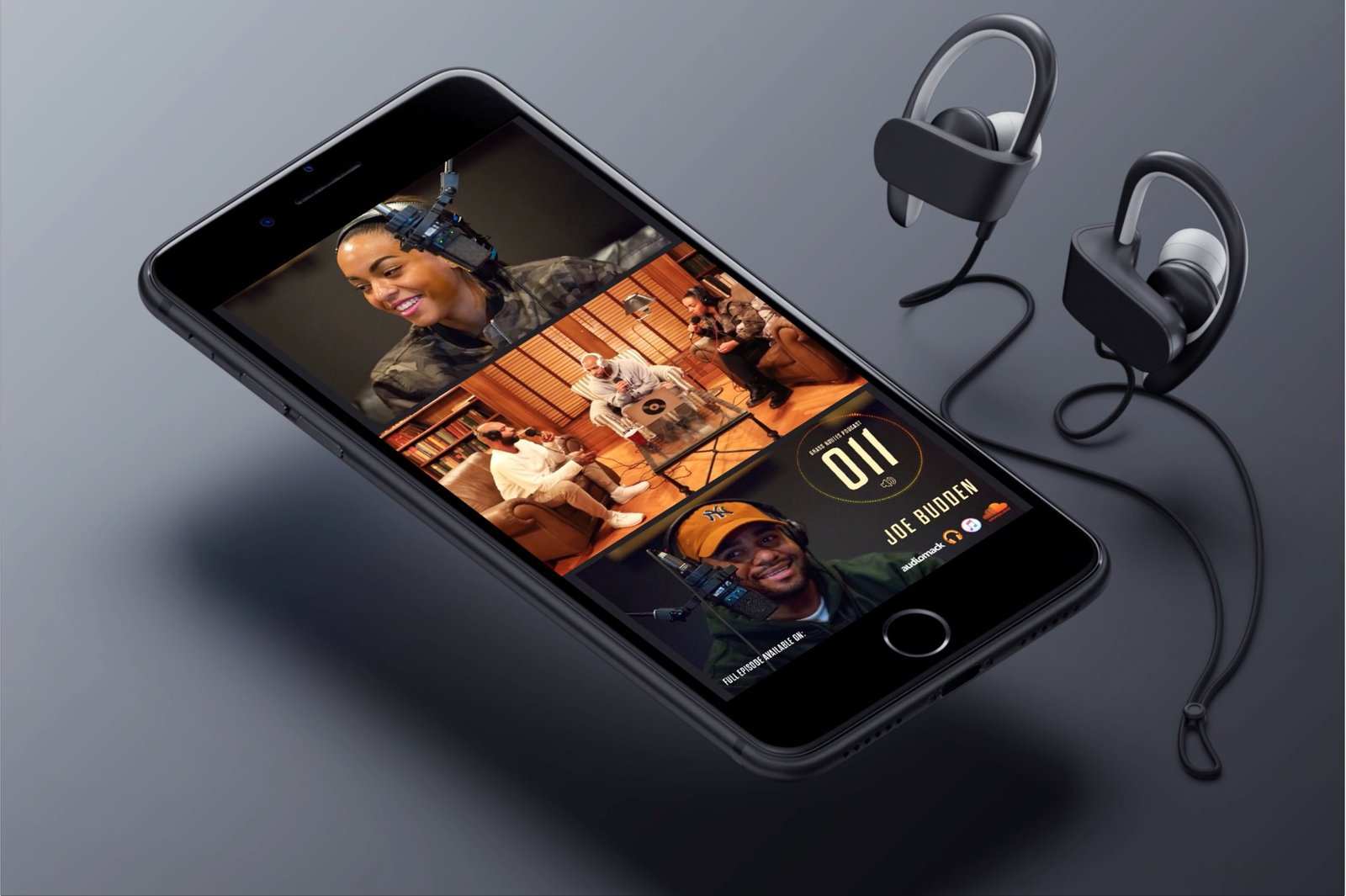 A phone showing the Grass Routes episode 011 cover with Joe Budden, next to a pair of earphones