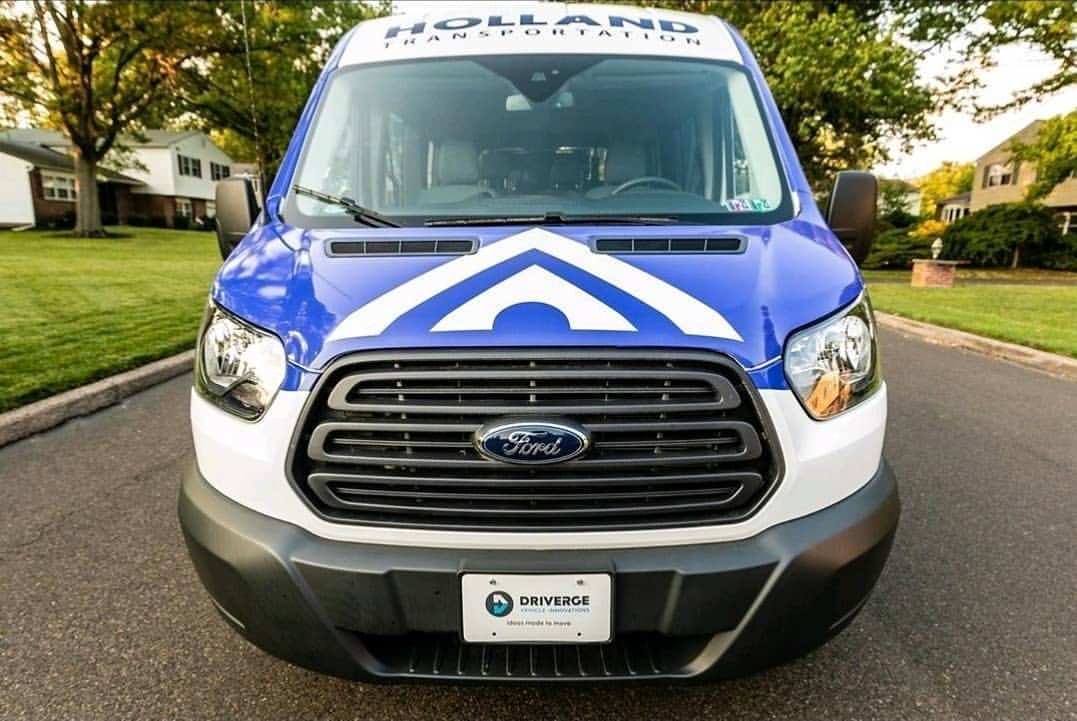 Van wrapped in navy and white with the Holland mark, front view