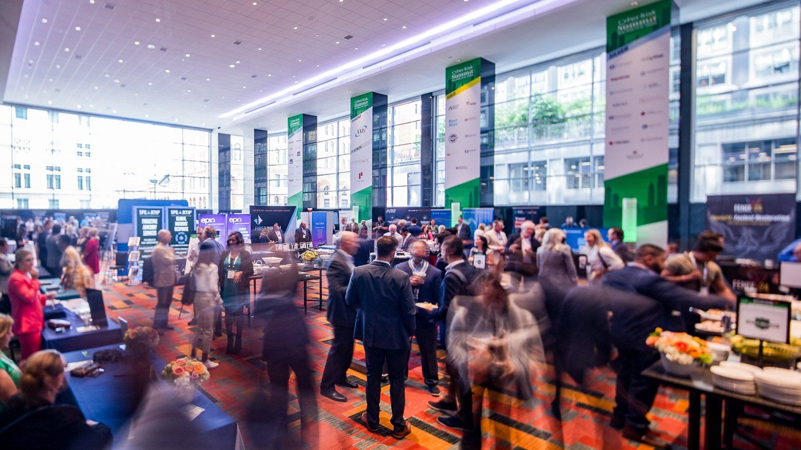 The summit floor during the event: sponsor columns wrapped in the green Cyber Risk Summit design around a crowded networking hall
