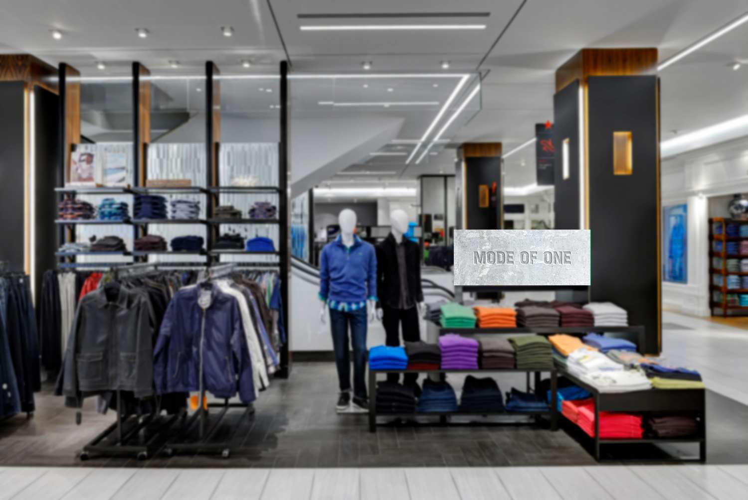 Mode of One at Macy’s, in store: the concrete Mode of One sign above the tables of folded knits