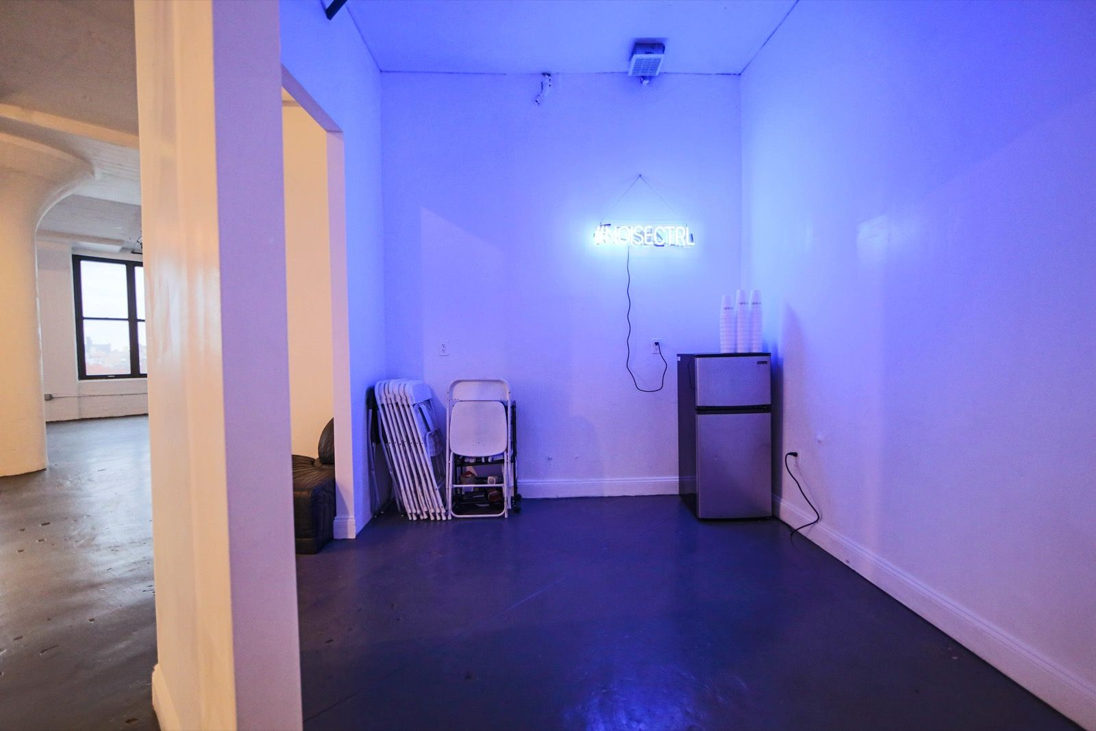 A blue-lit room in the loft with a neon sign