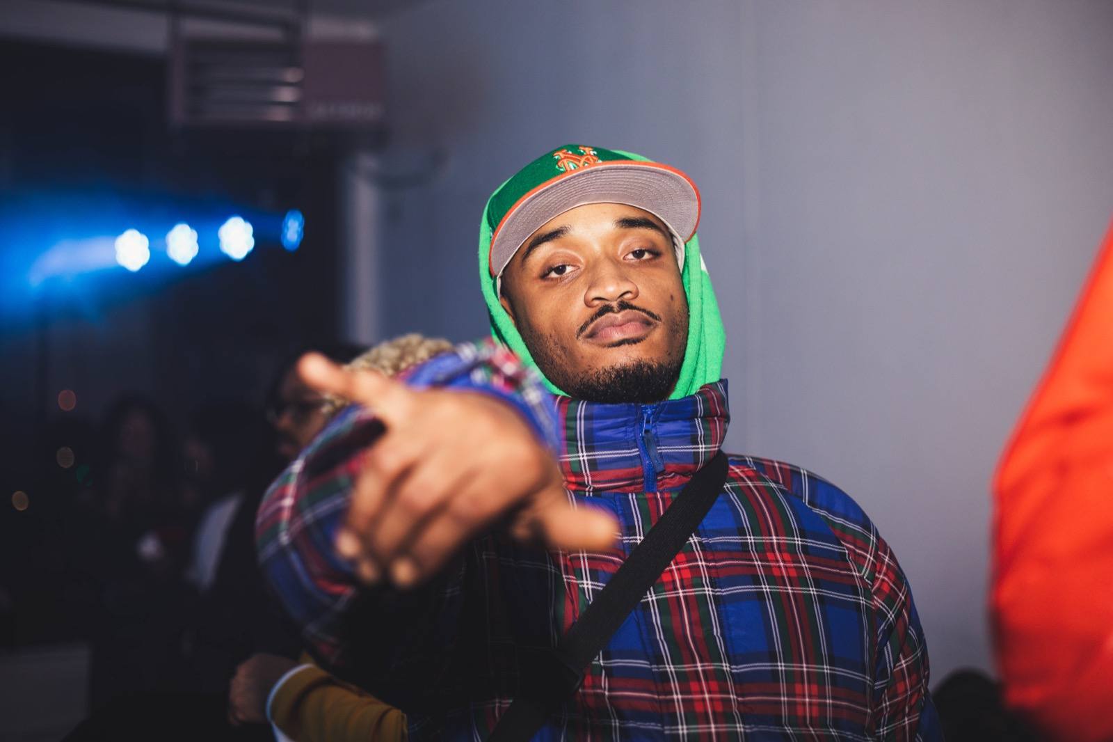 A guest in a green cap reaching toward the camera at a loft show
