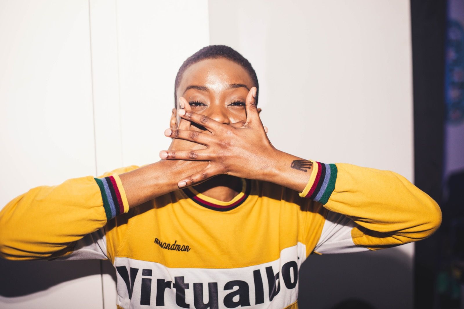 A guest in a yellow top covering their mouth, laughing