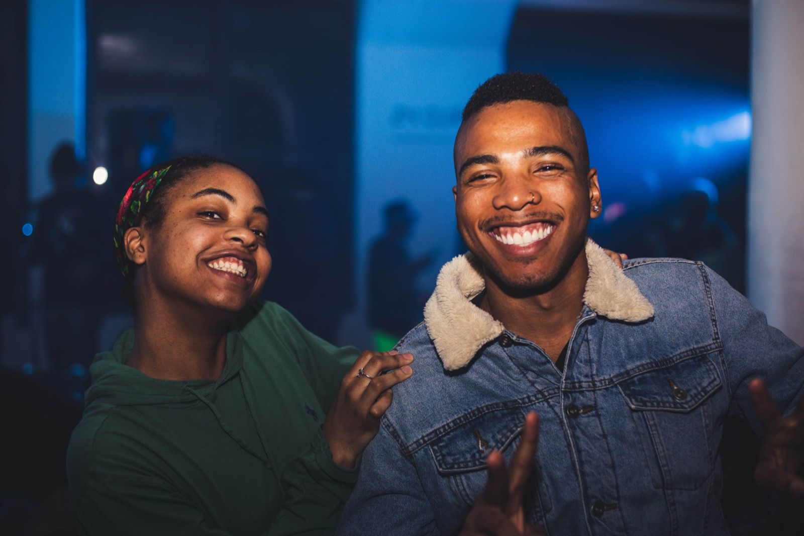Two guests laughing together in the blue stage light