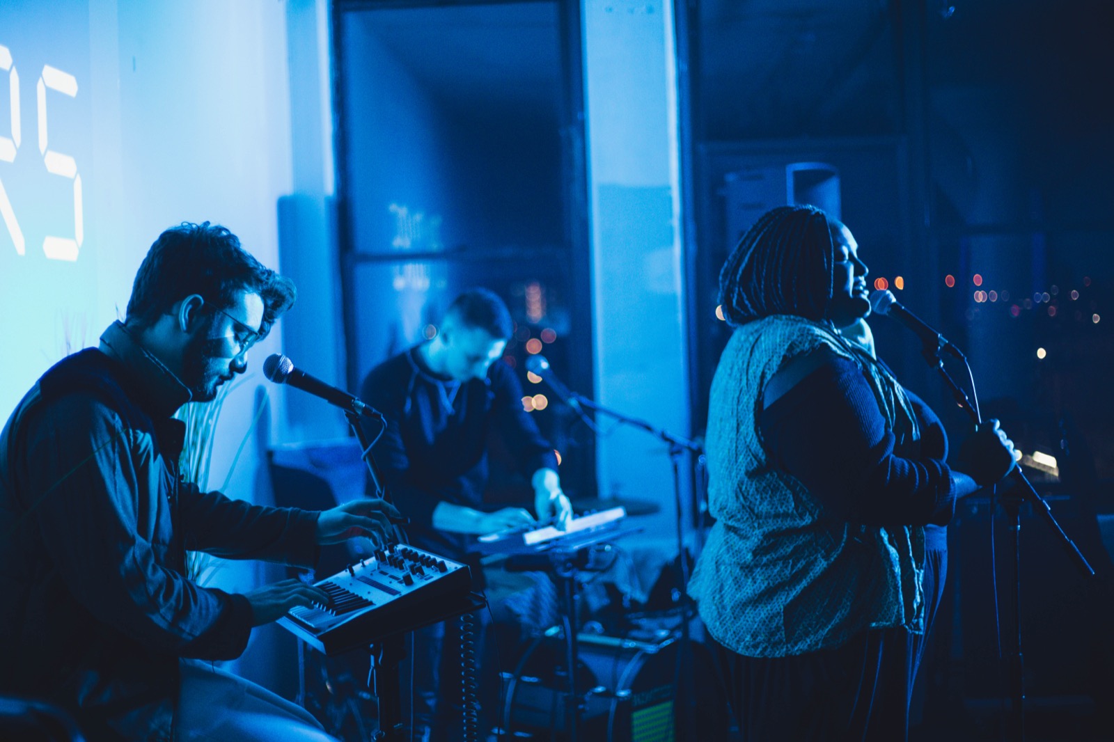 A keyboardist and a singer on stage at a loft show