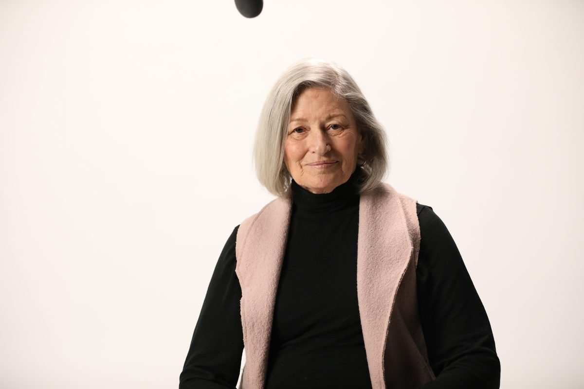 An older woman with silver hair in a black top and a pink vest, from the LetsGetChecked photoshoot